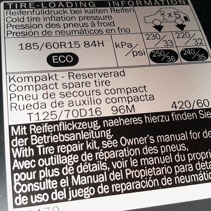 Tire-loading placard in the driver door jamb of a Toyota Yaris XP130 listing 185/60 R15 cold pressures and the compact spare
