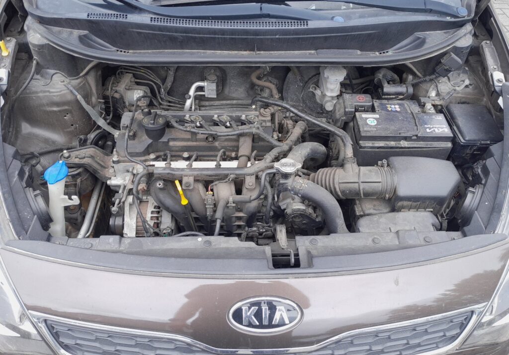 Kia Rio Mk3 (2011-2018) engine bay showing the 12 V battery location on the passenger side