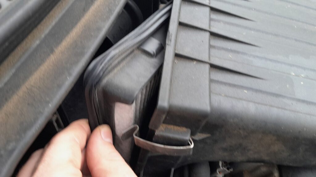 Suzuki Swift air cleaner cover lifted off, showing the filter seated in the lower housing