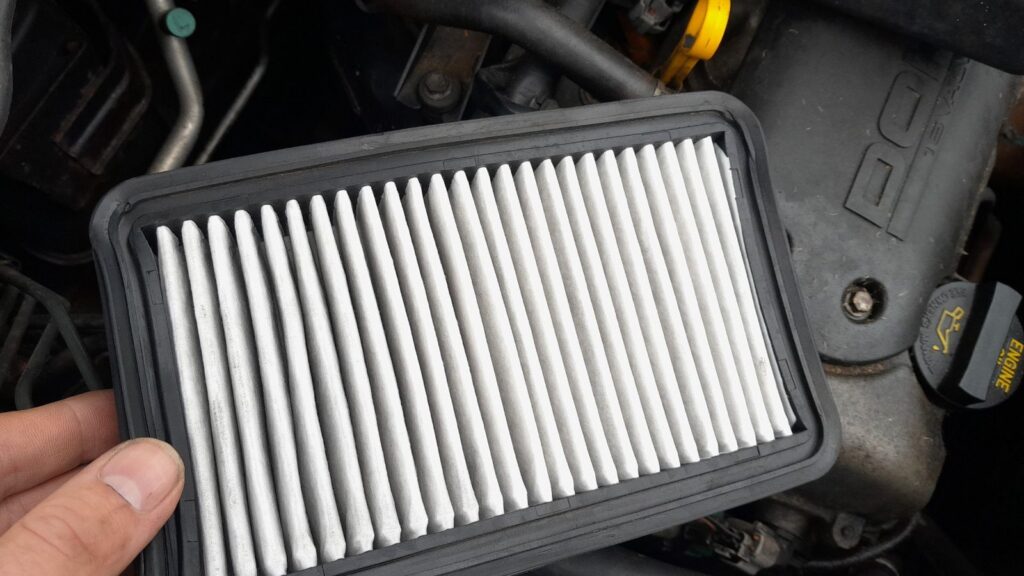 Removed pleated-paper air filter element from a Suzuki Swift 1.3, held up for inspection