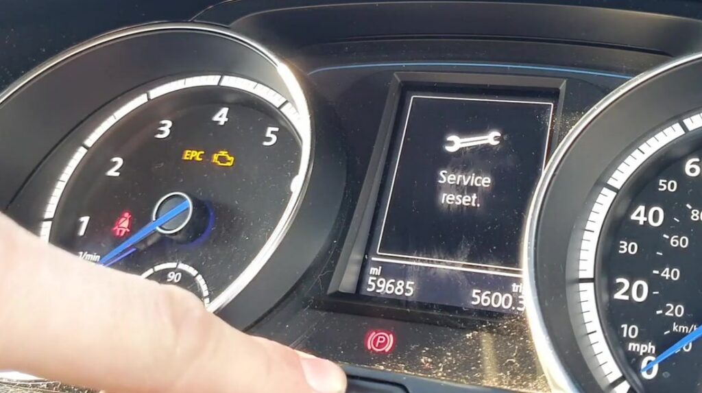 VW Golf Mk7 cluster showing the Service reset prompt with a finger on the reset button