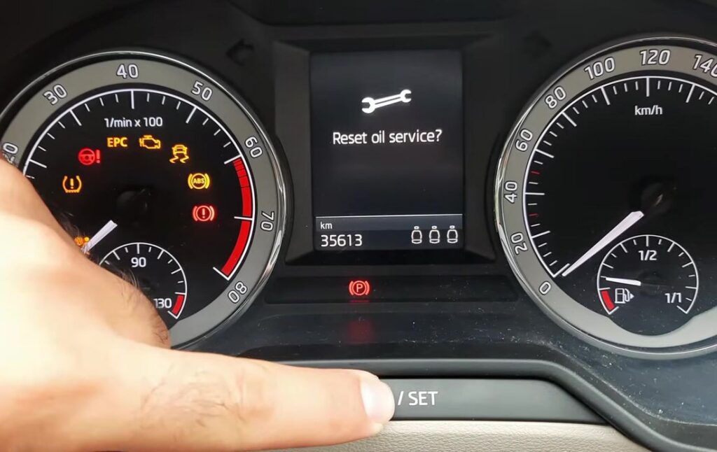 Skoda Octavia Mk3 (5E) MaxiDOT display showing the Reset oil service? prompt with the wrench icon, a finger on the /SET stalk button below the cluster
