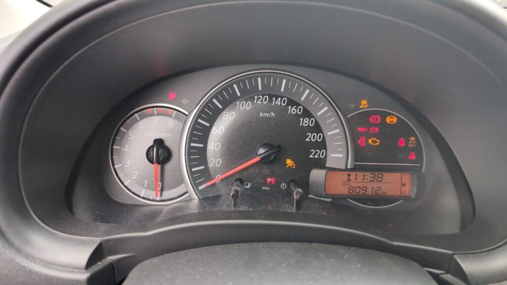 Nissan Micra K13 instrument cluster at startup, ideally with the spanner / SERVICE message visible. Wide enough to see the cluster LCD readout.