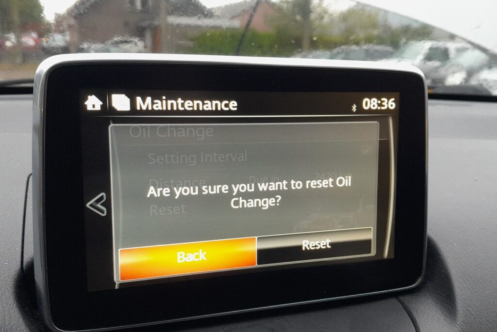 MZD Connect confirmation prompt reading Are you sure you want to reset Oil Change with Back and Reset buttons