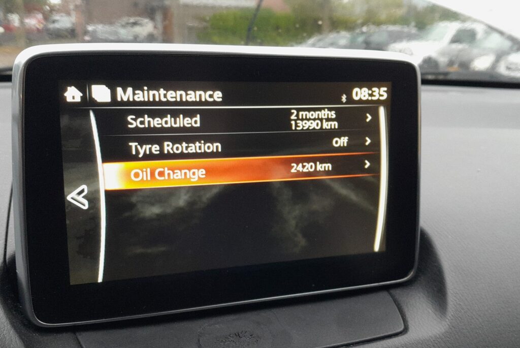 MZD Connect Maintenance menu on a Mazda 2 DJ showing Scheduled, Tyre Rotation and Oil Change items
