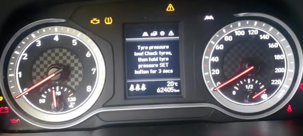 Hyundai i20 Mk2 (GB) instrument cluster showing the low tire-pressure warning and the message to hold the tire-pressure SET button for 3 seconds.