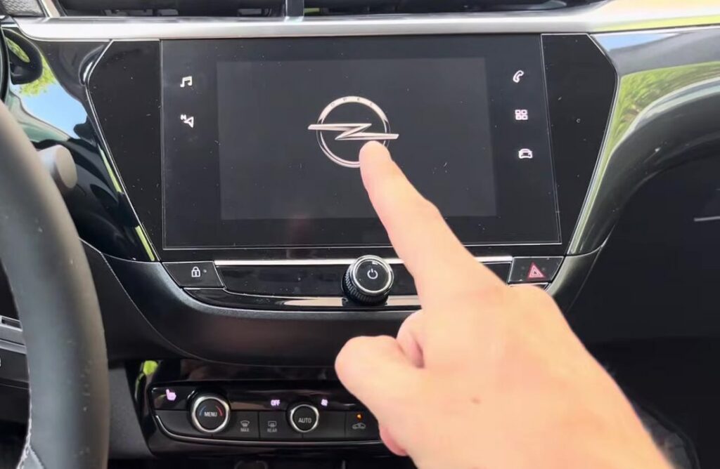Vauxhall Corsa F infotainment touchscreen rebooting to the Opel logo, with the round power/volume knob visible directly below the screen
