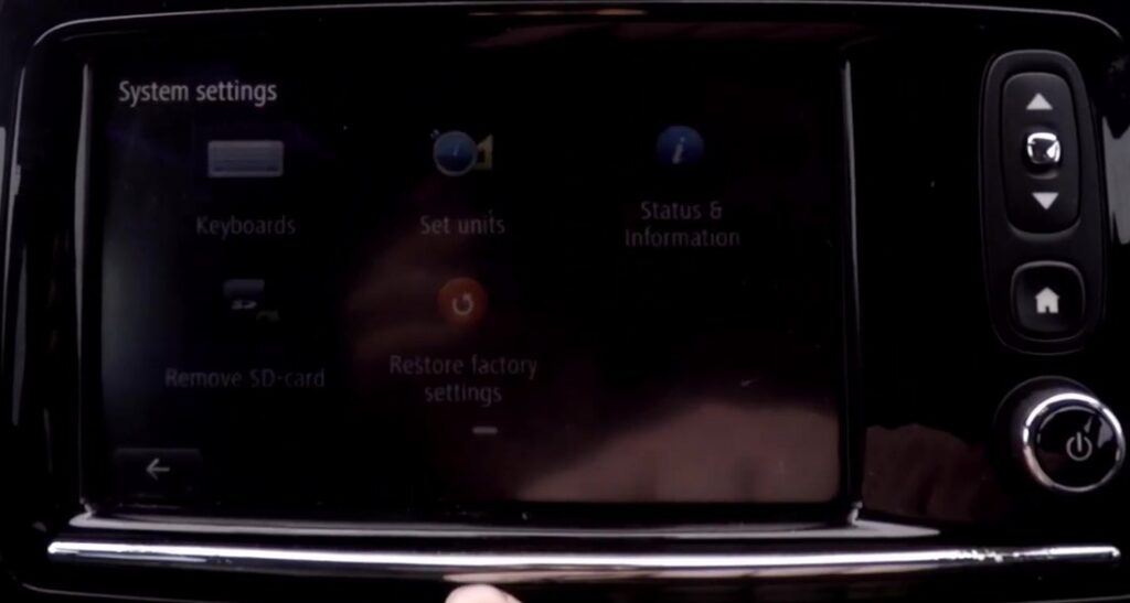 Renault R-Link touchscreen showing the System settings menu with the Restore factory settings option (orange icon), plus the on/off button on the right-hand control column.