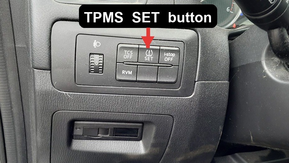 Red arrow pointing to the TPMS SET button on the Mazda CX-5 dashboard switch panel
