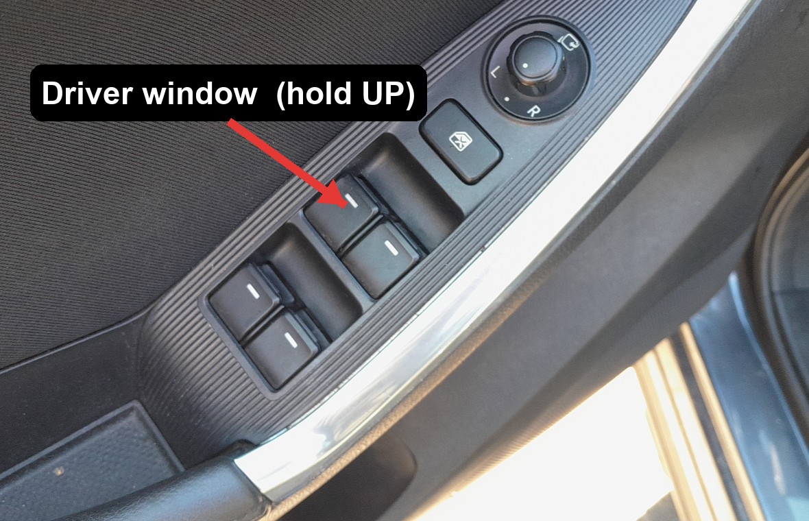 Red arrow pointing to the driver front window switch on the Mazda CX-5 door panel