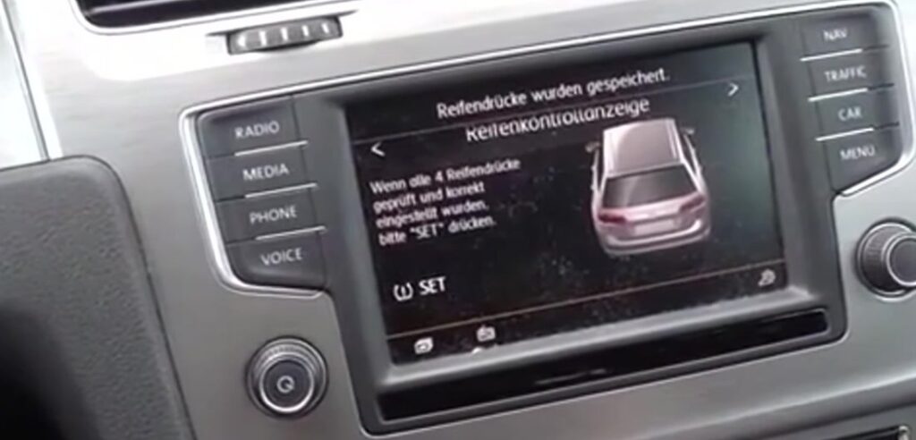 Volkswagen Golf Mk7 Composition Media touchscreen showing the Reifenkontrollanzeige (tyre-monitoring) menu with the on-screen SET soft-key used to store new reference tyre pressures