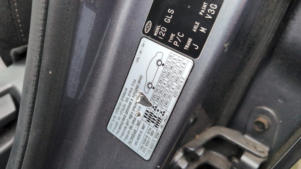 Hyundai i20 Mk2 tyre pressure placard in the driver's door aperture showing recommended pressures.