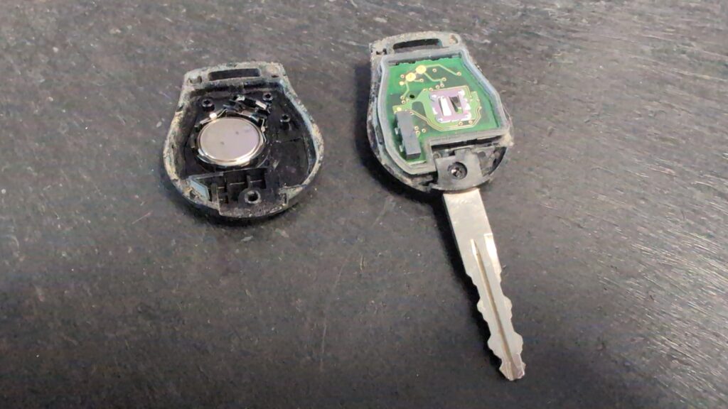 Nissan Micra K13 key fob opened, CR1620 coin cell visible.