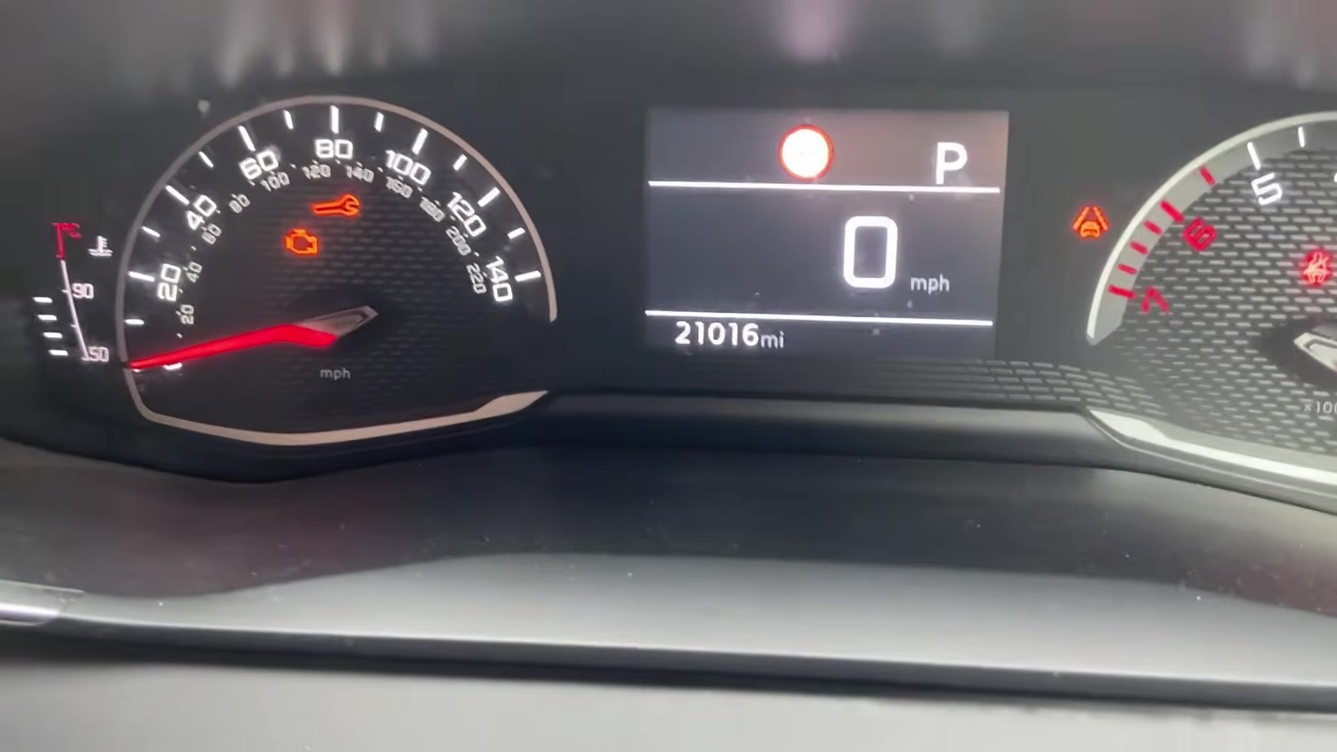Peugeot 208 Mk2 instrument cluster with the orange service spanner warning lit, odometer 21016 miles, gear selector in P.