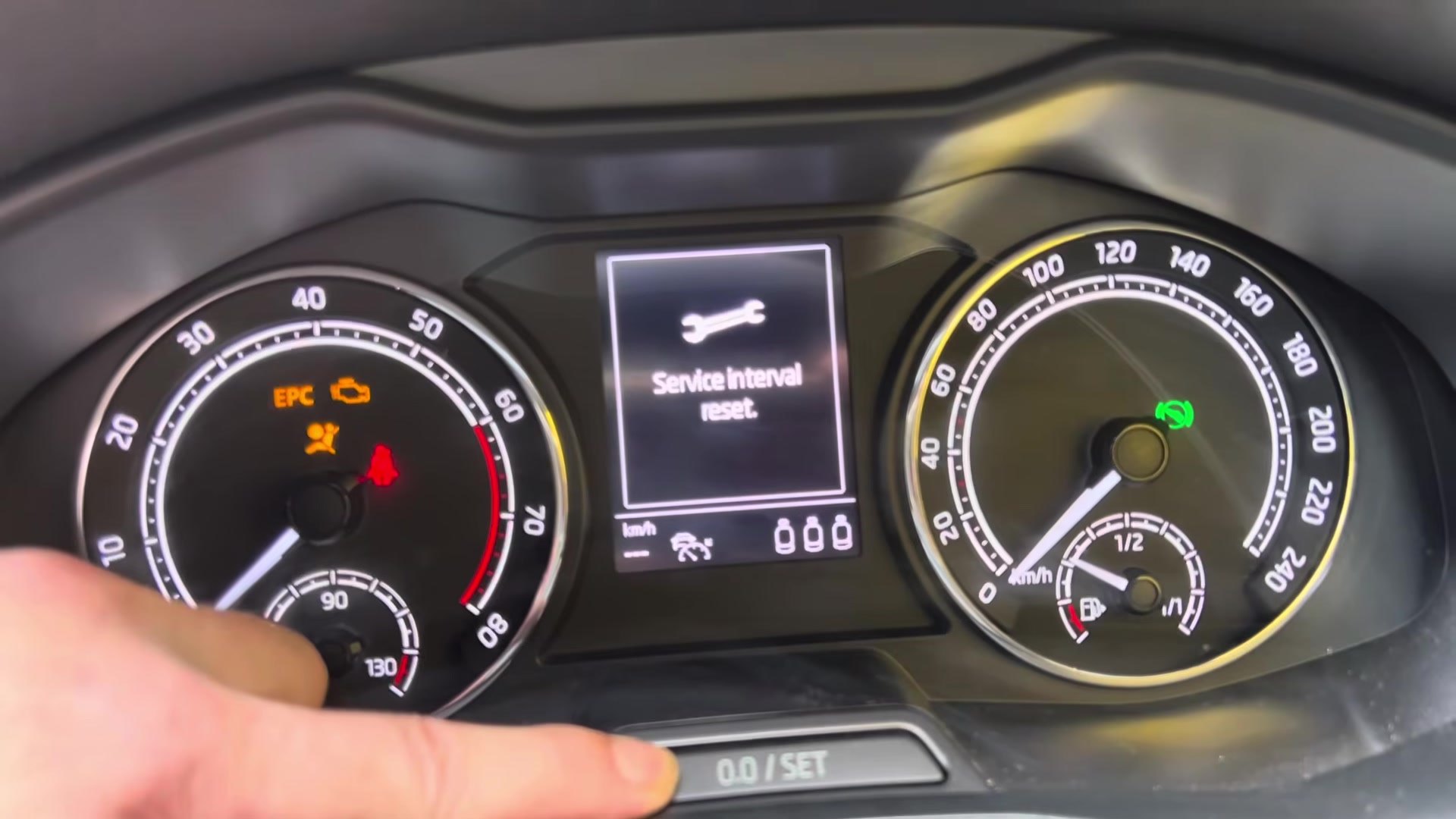 Skoda Scala NW cluster showing the 'Service interval reset.' confirmation message with a finger on the 0.0/SET button.