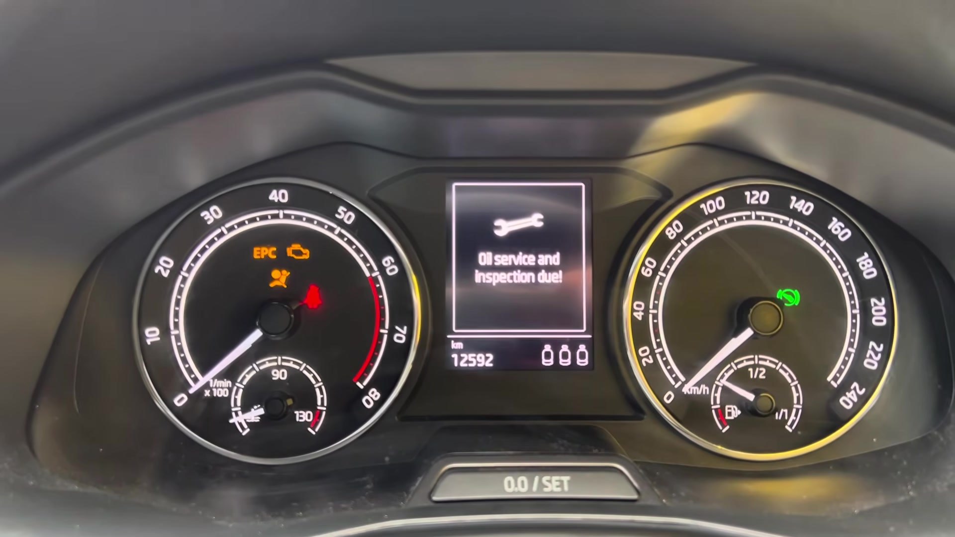 Skoda Scala NW analog instrument cluster showing the wrench 'Oil service and inspection due!' message at ignition-on, with the 0.0/SET trip-reset button below.