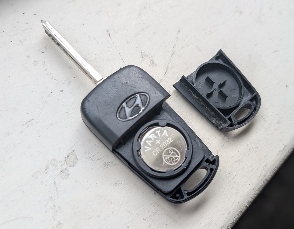 Opened Hyundai i20 Mk1 (PB) remote key showing the CR2032 coin cell and removed back cover
