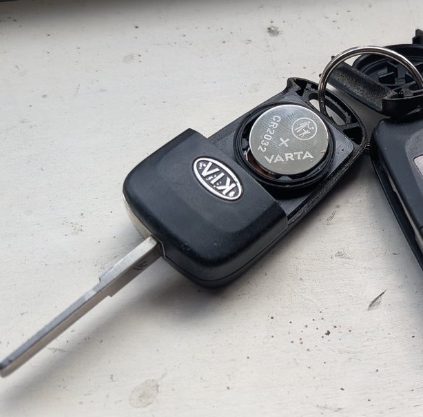 Kia remote-head key opened showing the CR2032 coin cell, positive side up