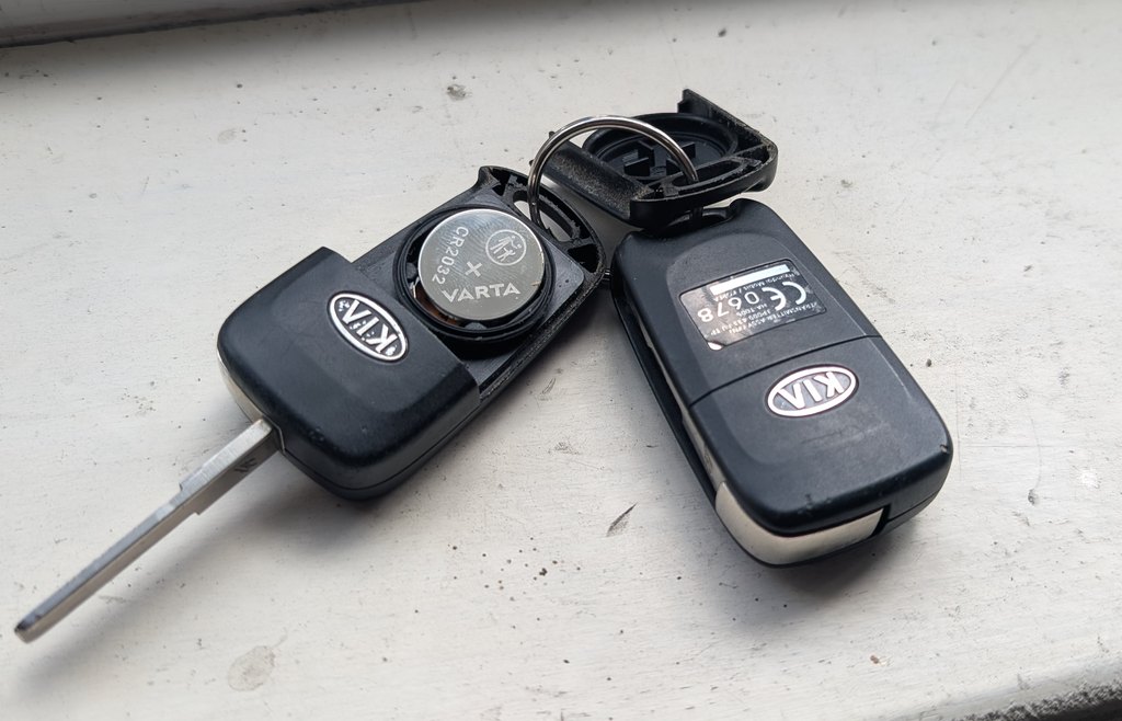 Kia Venga remote-head key opened showing the CR2032 cell, beside the flip key