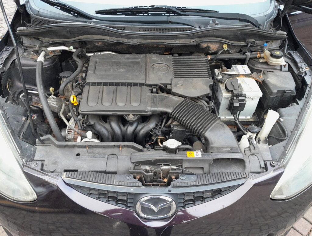 Mazda 2 DE engine bay with the 12V battery on the right