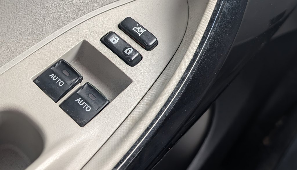 Driver-door power window switches on the Toyota iQ, both with one-touch AUTO
