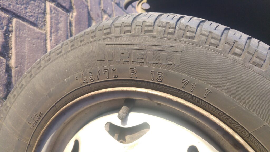 A Pirelli 145/70 R13 tyre on a steel wheel with plenty of tread remaining but visibly aged, hardened rubber
