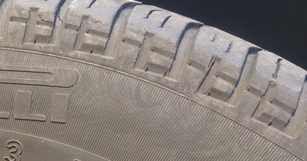 Close-up of fine cracks and crazing at the base of the tread grooves and shoulder of an aged tyre, despite plenty of remaining tread depth