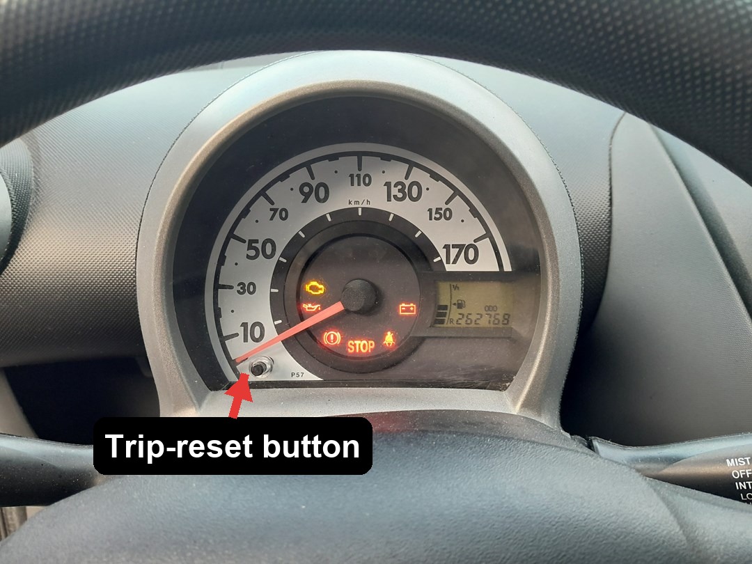 Toyota Aygo instrument cluster with an arrow marking the trip-reset button
