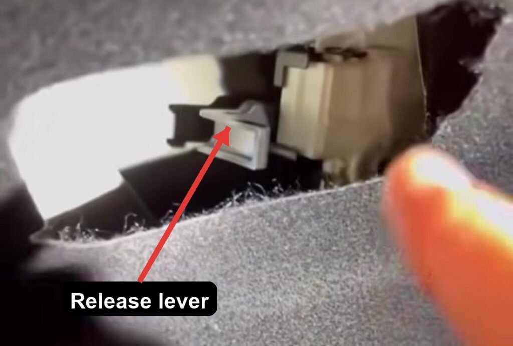 Manual fuel-filler release lever behind the boot side trim on a Toyota C-HR, arrowed