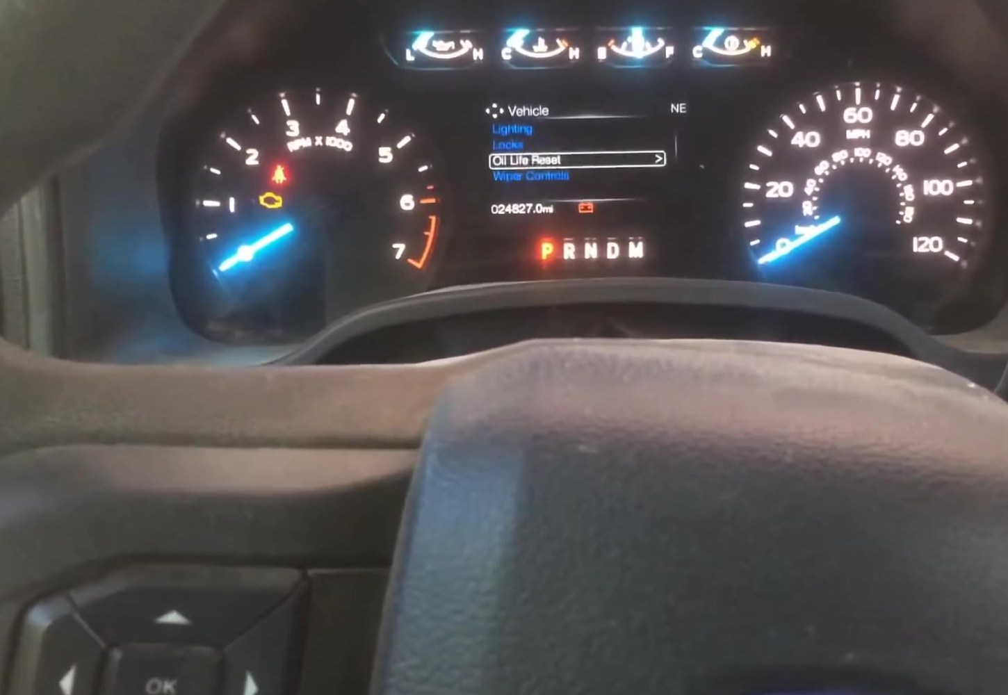 Ford F-150 P552 instrument-cluster productivity screen with Oil Life Reset highlighted, and the left steering-wheel OK and arrow buttons below