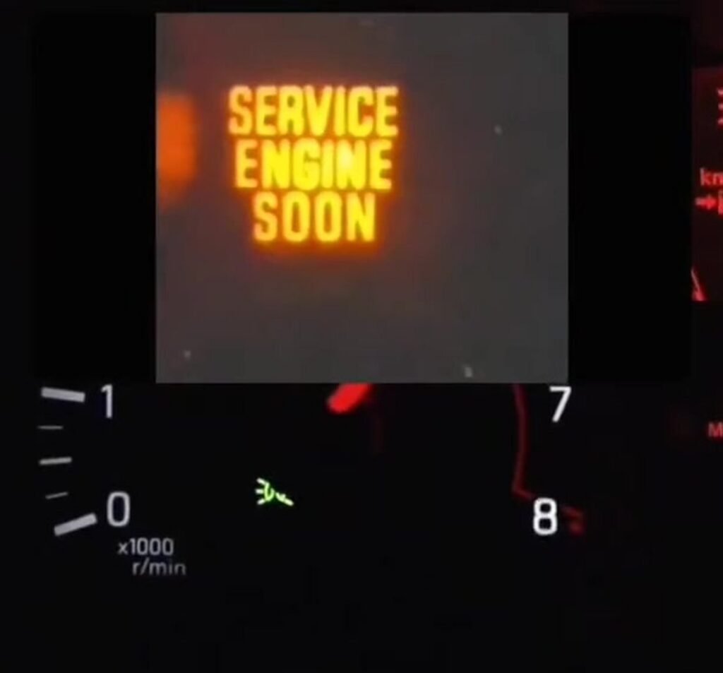Service Engine Soon text warning lamp lit on a US-market Nissan Juke F15 instrument cluster during self-diagnostic mode