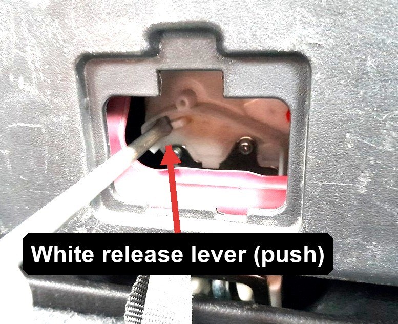 White plastic tailgate release lever pushed with a screwdriver on a Mitsubishi Outlander