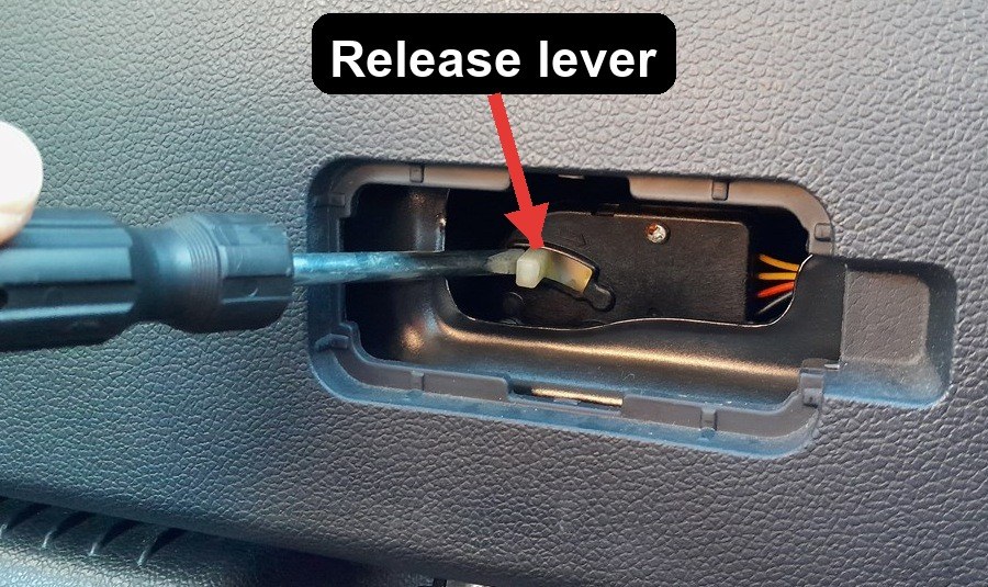 White emergency release lever exposed inside a Kia Rio Mk3 tailgate, arrowed, being pushed to the side