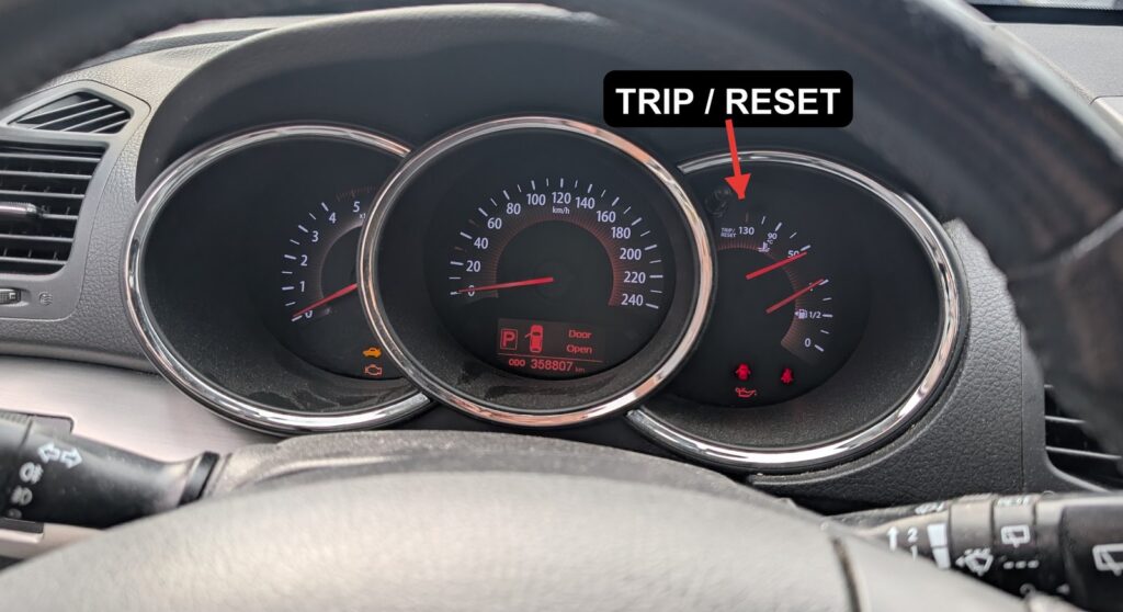 Kia Sorento XM instrument cluster with the TRIP/RESET button arrowed