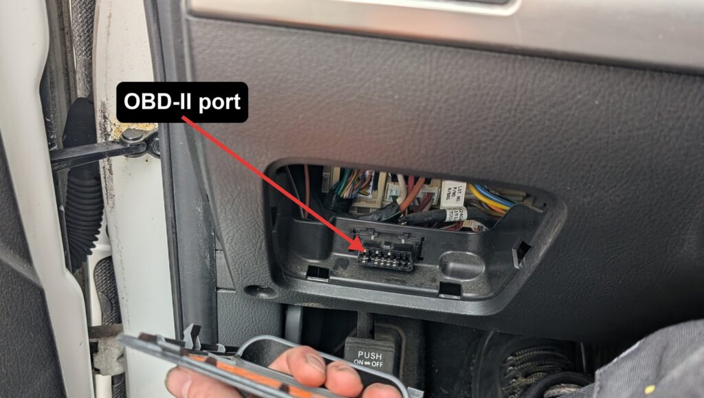 Kia Sorento XM OBD-II port under the dash, arrow marking the 16-pin connector