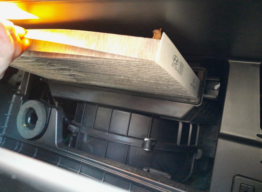 Cabin pollen filter being withdrawn from behind the Hyundai i20 glovebox