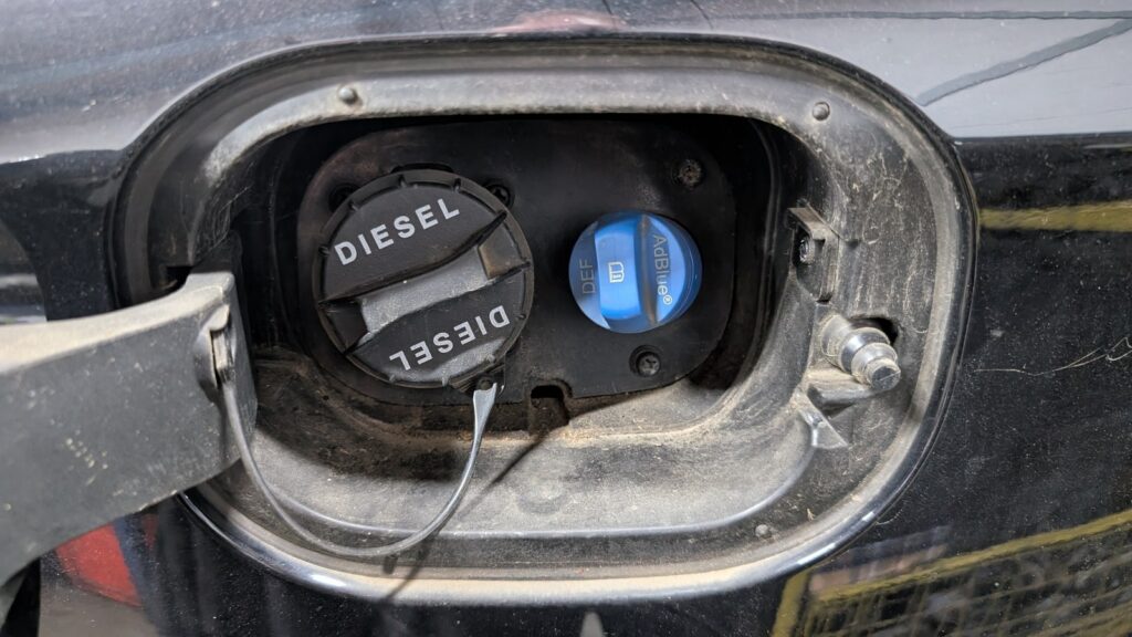 Blue AdBlue (DEF) filler cap next to the black diesel cap under the fuel flap of a Hyundai i30 diesel