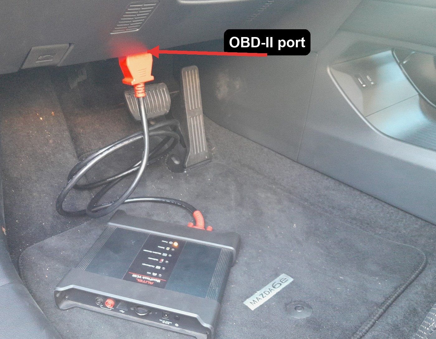 OBD-II port location on a Mazda 6e, above the brake pedal