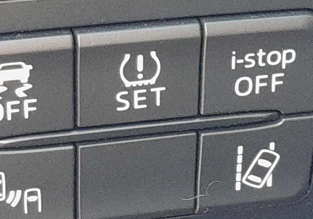 The TPMS SET switch on the lower dash of a Mazda 2 DJ